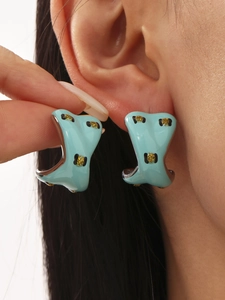 Detailed close-up of light blue enamel C-hoop earring with leopard spots on model ear