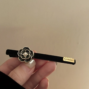 Close-up of velvet camellia hair clip featuring black enamel petals and pearl center