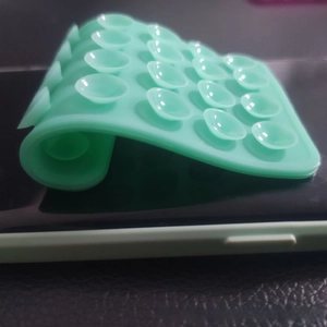 Macro shot of mint green silicone suction cup pad for mobile phones on a dark surface