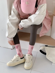 Detail of pink crew socks with heart patterns worn with white sneakers on wooden steps