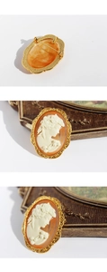 Macro detail of vintage cameo brooch showing the golden textured frame and pin back