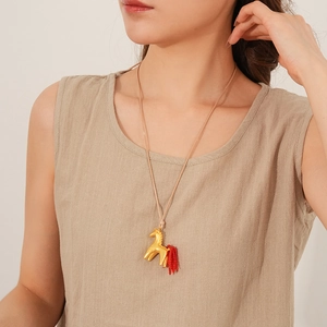 Long wax rope necklace with gold horse pendant and vibrant red fringe tail on model