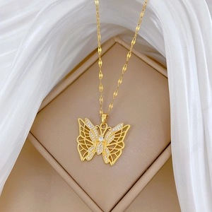 Detail showing a gold butterfly pendant with inlaid zircons on a beige jewelry box