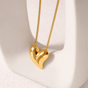 Detail of 18k gold heart pendant on a smooth snake chain with premium metal luster