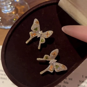 Elegant gold bow earrings with white zircon and colorful gemstones in a velvet box