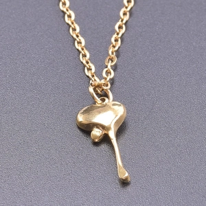 Detail shot of golden stainless steel necklace featuring a polished heart drop pendant