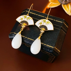 Detail of fan-shaped earring with bamboo pattern and white teardrop bead on jewelry box