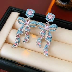 Détail de boucles d'oreilles nœud vintage avec pierres roses et perles turquoise en boîte