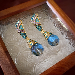 Gros plan de boucles d'oreilles vintage avec cristaux bleus et détails dorés