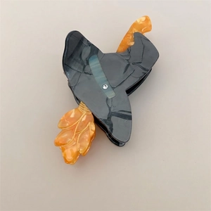 Detailed close-up of a wizard hat and broom hair claw clip made from marble acetate