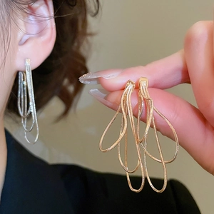 Gros plan de boucles d'oreilles multicouches en chaîne serpent dorée et argentée