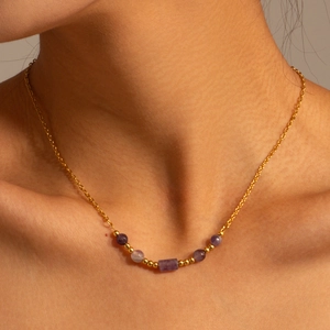 Macro view of 18K gold plated necklace with purple turquoise beads on a model collarbone