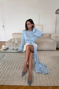Dettaglio maglione in maglia celeste con lunghi lacci a nastro e un design aderente