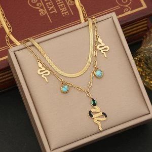 Detailed shot of double-layered gold snake necklace with green gems on jewelry box