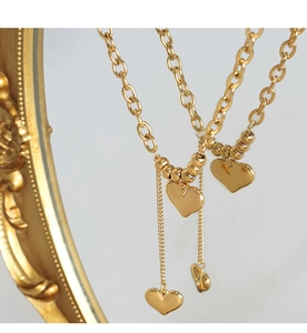 Macro detail of layered golden 18K gold plated titanium necklace with heart charms