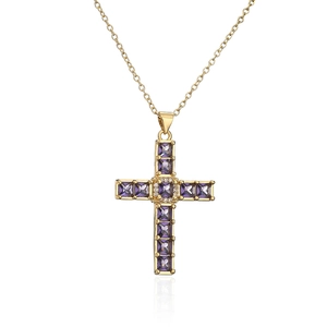 Macro detail of gold cross pendant with purple gemstones and zircons on fine chain