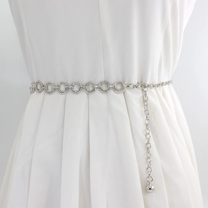 Adjustable silver metal ring chain belt with ball pendant on a white dress