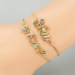 Detail of Mama and Love gold bracelets with rainbow zircons worn on the wrist