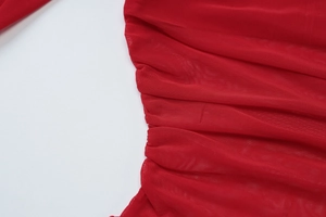 Detailed close-up of red mesh fabric with elegant pleated texture and sheer finish