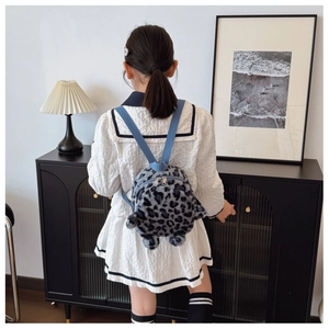 Detail of plush leopard print kid backpack with contrasting blue straps and soft texture
