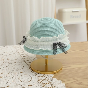 Détail du chapeau de paille vert menthe avec dentelle blanche et nœuds noirs élégants