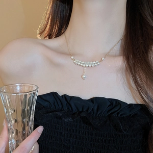 Close-up of double-layer faux pearl necklace with gold chain on model neck