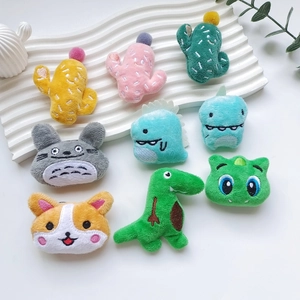 Assorted cute plush cartoon brooches featuring cactus and dinosaur on a white display