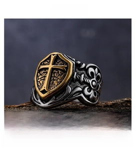 Macro shot of vintage silver steel ring featuring golden cross shield and ornate carving