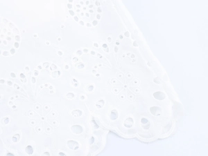Close-up of white floral embroidery with hollow out details and scalloped hemline