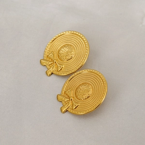 Retro gold-plated hat earrings with woven texture and bow detail on gray fabric
