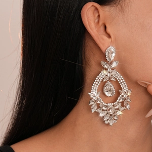 Close-up of sparkling flower drop earrings with rhinestones on a female model