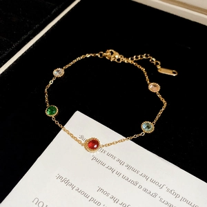 Detailed macro view of gold-plated bracelet with multi-colored zircons on black velvet