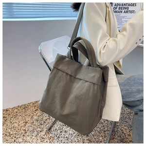 Army green nylon tote bag shown in a lifestyle scene for daily commuting and school
