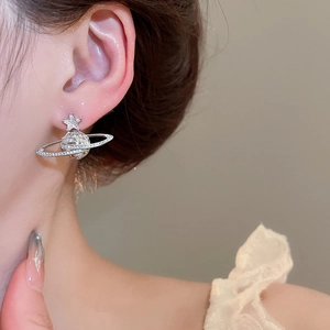Close-up of silver planet stud earrings with cubic zirconia and star detail on model