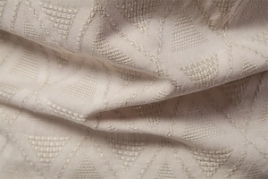 Macro shot of off-white jacquard fabric with geometric triangle pattern and soft texture
