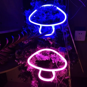 Close-up of blue and pink LED mushroom neon signs on a festive Christmas tree background