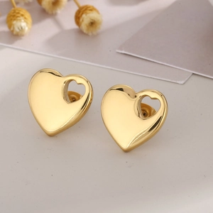 Macro shot of polished gold-tone hollow heart stud earrings with elegant glossy finish