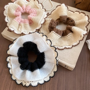 Close-up of three knitted lace hair scrunchies on a book showing soft textures and details