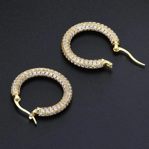 Detail of gold hoop earrings featuring three rows of sparkling white zircon stones