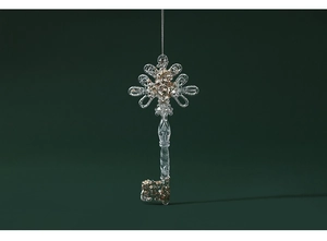 Close-up of clear acrylic key ornament with champagne gold glitter on green background