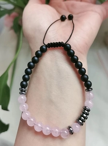 Détail d'un bracelet code Morse avec quartz rose et perles noires mates sur la main