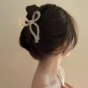Close-up of a matte green bow-shaped hair claw clip holding an elegant updo ponytail