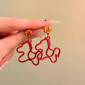 Close-up of red enamel Fu character earrings with gold cutout animal pattern charm