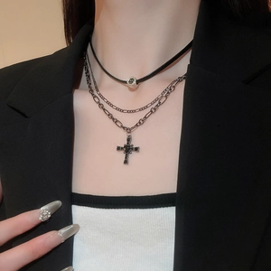 Dettaglio di una collana punk a strati con choker nero e ciondolo a croce nera