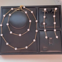 Detail view of a white pearl jewelry set with necklace and tassel earrings on black tray