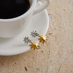 Elegant two-tone star drop earrings with gold and silver polished finish on a marble surface