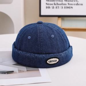 Close-up of denim blue cotton docker hat with aimax embroidery on a white table