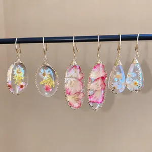 Pendientes hechos a mano de resina con flores secas reales en una barra de muestra