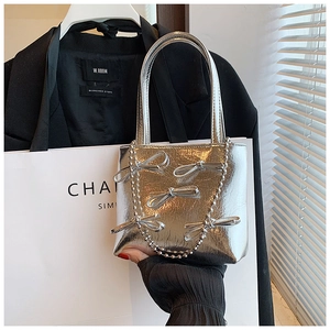 Close-up of silver metallic handbag with bow details and chic beaded chain strap
