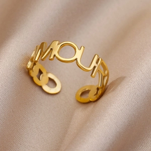 Detail shot of golden adjustable AMOUR letter ring on champagne silk background